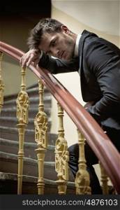 Elegant man leaing on a wooden handrail