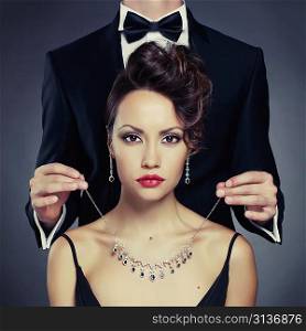 Elegant man on a beautiful woman wears a necklace