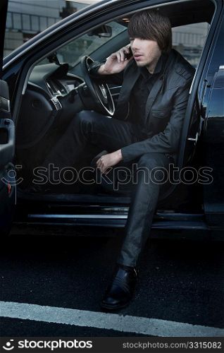Elegant man talking over cellphone in his car