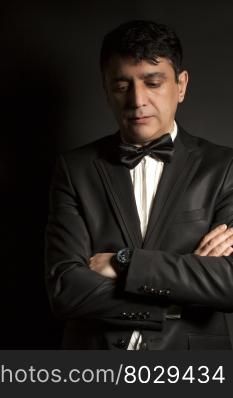Elegant man wearing black bow tie and black suit on black background