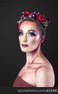 Elegant model with bright New Year's Eve make-up in a wreath of Christmas toys. Studio shot.
