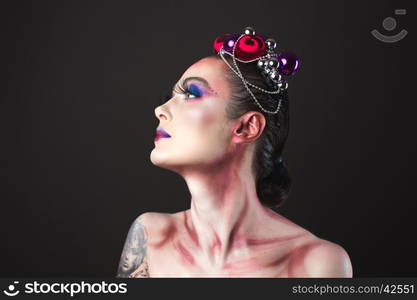 Elegant model with bright New Year's Eve make-up in a wreath of Christmas toys. Studio shot.