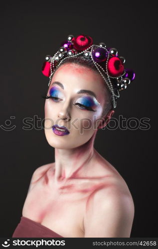 Elegant model with bright New Year's Eve make-up in a wreath of Christmas toys. Studio shot.