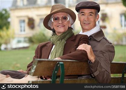 Elegant older couple sitting on a bench