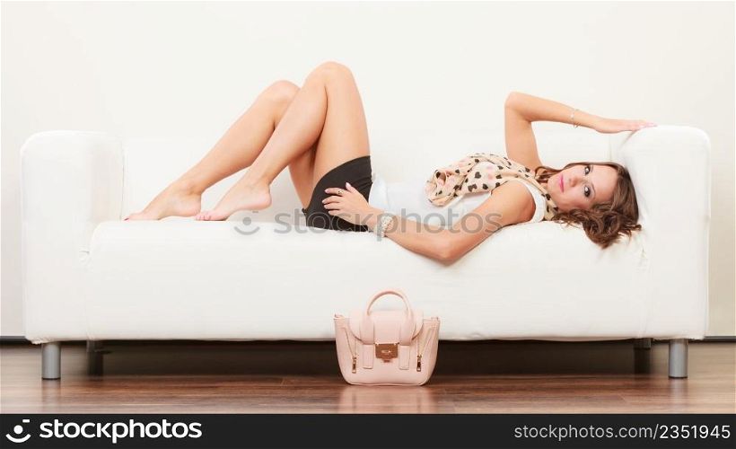 Elegant outfit. Female fashion. Girl in fashionable clothes posing on sofa bag handbag on floor.