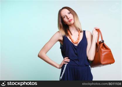 Elegant outfit. Stylish woman fashionable girl with brown leather handbag bag on green. Fashion and female beauty.
