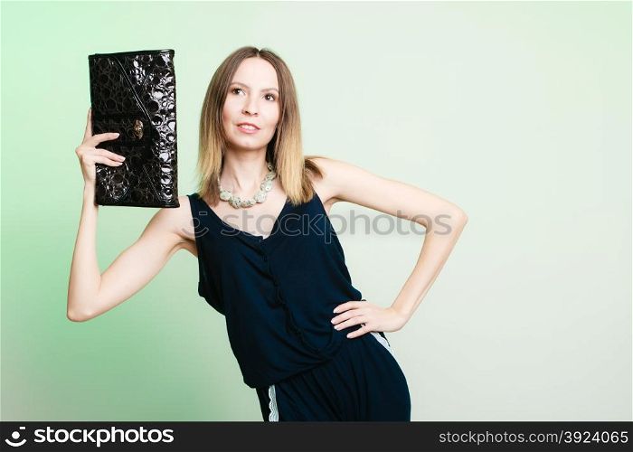 Elegant outfit. Young stylish woman fashionable girl holding black handbag on green. Fashion and female beauty. Studio shot.