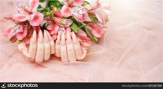 Elegant pastel pink natural manicure. Female hands  with flowers alstroemeria  on pink silk background.