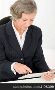 Elegant senior businesswoman working on touch-screen tablet computer