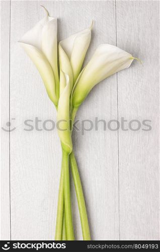 Elegant spring flower, calla lily on rustic wooden table. For wedding background image. Top view with copy space