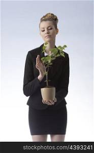 elegant successful business woman with blonde hair style wearing dark suit holding rich money plant