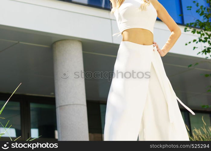 Elegant unrecognizable woman presenting fashionable urban outfit. White crop top and trousers culottes.. Woman wearing high heels and culottes