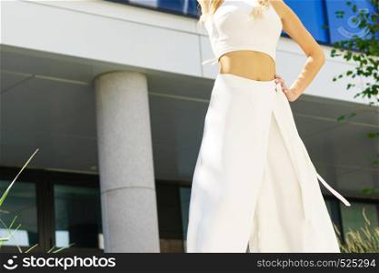 Elegant unrecognizable woman presenting fashionable urban outfit. White crop top and trousers culottes.. Woman wearing high heels and culottes
