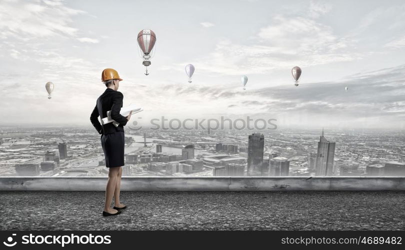 Elegant woman engineer. Young woman architect in hardhat holding project in hand