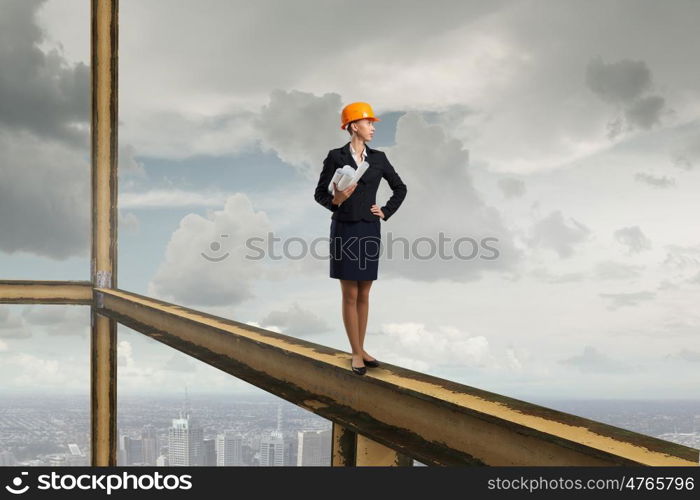 Elegant woman engineer. Young woman architect in hardhat holding project in hand