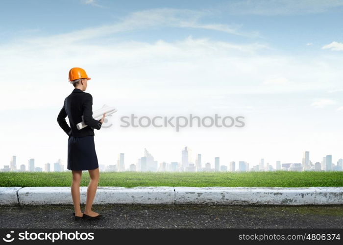 Elegant woman engineer. Young woman architect in hardhat holding project in hand