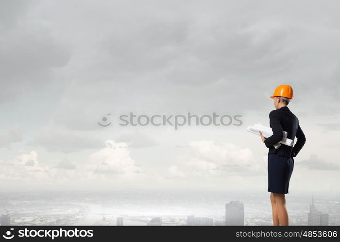 Elegant woman engineer. Young woman architect in hardhat holding project in hand