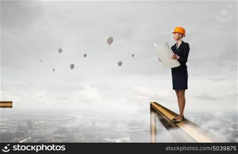 Elegant woman engineer. Young woman architect in hardhat holding project in hand
