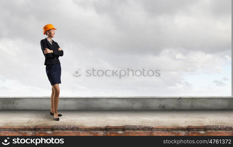 Elegant woman engineer. Young woman architect in hardhat on building roof