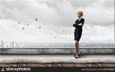 Elegant woman engineer. Young woman architect in hardhat on building roof