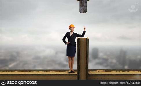 Elegant woman engineer. Young woman architect in hardhat standing on balk
