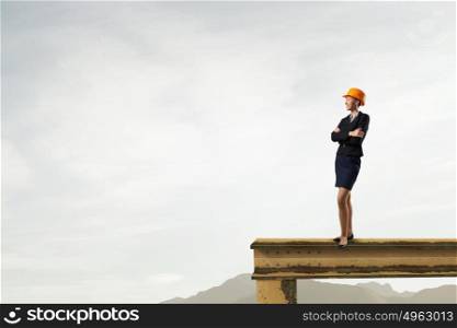 Elegant woman engineer. Young woman architect in hardhat standing on balk