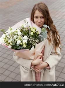 elegant woman outdoors holding bouquet flowers