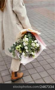 elegant woman outdoors walking holding bouquet flowers