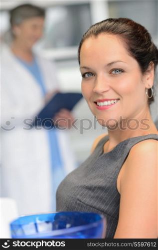 Elegant woman patient at dental surgery smiling dentist in background