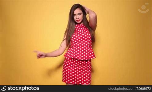 Elegant woman wearing red polka dots dress with hands on her hips