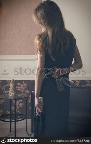 Elegant woman , with a bottle of champagne and flut , she is hidden , the flut , waiting for surprise , indoor shot