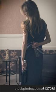 Elegant woman , with a bottle of champagne and flut , she is hidden , the flut , waiting for surprise , indoor shot