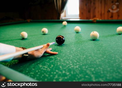 elegant young man in a dark suit plays billiards