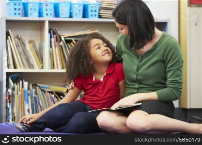 Elementary Pupil Reading With Teacher In Classroom