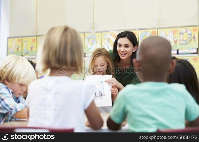 Elementary Pupil Showing Drawing To Classmates In Classroom