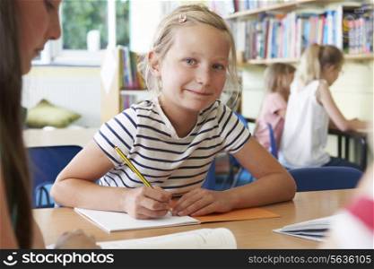 Elementary School Pupil Working At Desk In Classroom