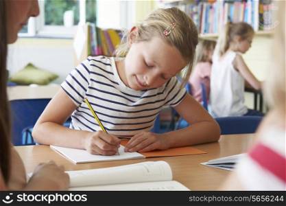Elementary School Pupil Working At Desk In Classroom
