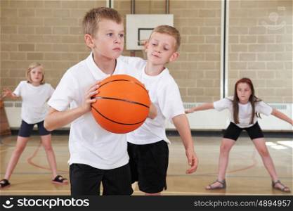 Elementary School Pupils Playing Basketball In Gym