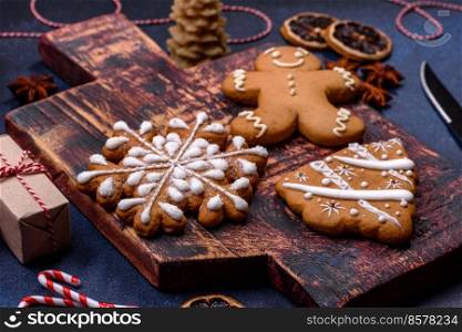 Elements of Christmas decorations, sweets and gingerbread on a wooden cutting board against a dark concrete background. Preparing for the holiday. Elements of Christmas decorations, sweets and gingerbread on a wooden cutting board