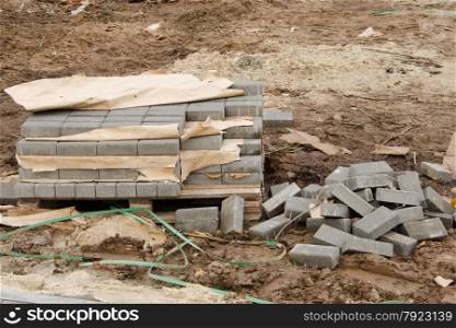 Elements of paving slabs stacked on a pallet in a stack and heap on the ground lying around on the street. Elements of paving slabs lying on the ground
