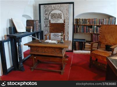 Elements of the old life - table, chair, ink, candle, books, bookshelves.
