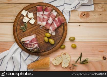 elevated view bacon olives cheese bread slices wooden circular board table