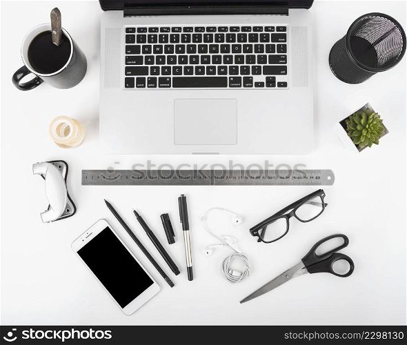 elevated view black coffee laptop cellphone stationeries white backdrop