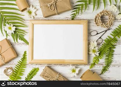 elevated view blank frame surrounded by gifts leaves white flowers. High resolution photo. elevated view blank frame surrounded by gifts leaves white flowers. High quality photo