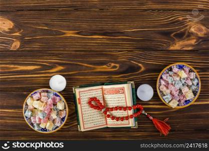 elevated view candles red prayer beads with holy kuran lukum bowls wooden table