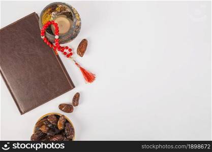 elevated view closed diary with prayer beads fresh dates white backdrop. Resolution and high quality beautiful photo. elevated view closed diary with prayer beads fresh dates white backdrop. High quality beautiful photo concept