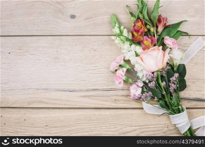 elevated view colorful flower bouquet tied with white ribbon wooden desk