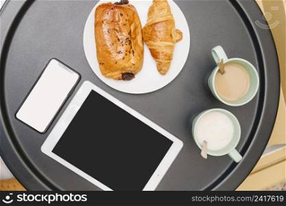 elevated view croissants milk tea electronic gadgets table