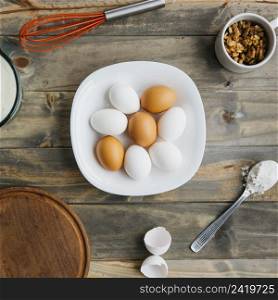 elevated view eggs flour walnut with whisk wooden background
