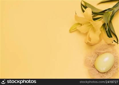 elevated view fresh lily flower with easter egg nest yellow backdrop